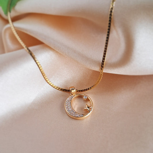 Golden moon and star necklace with sparkling stones on beige background