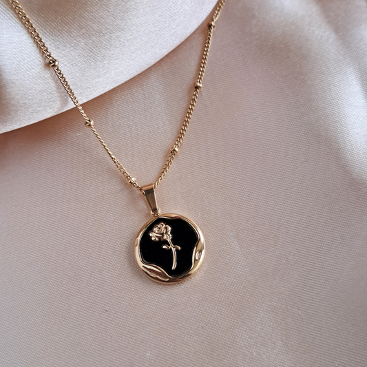 Golden rose necklace with round pendant on black background
